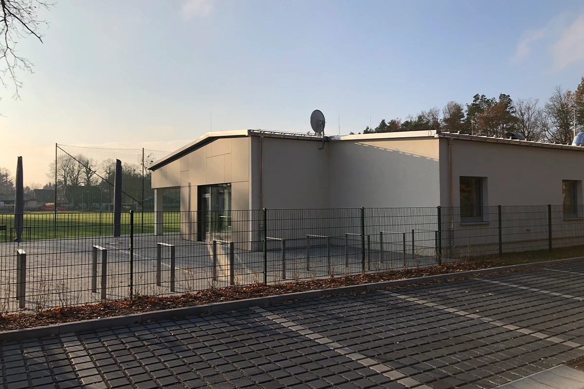 Funktionsgebäude am Sportplatz Michendorf mit moderner Außenhülle, heller Fassade und Teilverkleidung nach Fassadensanierung mit WDVS und VHF.