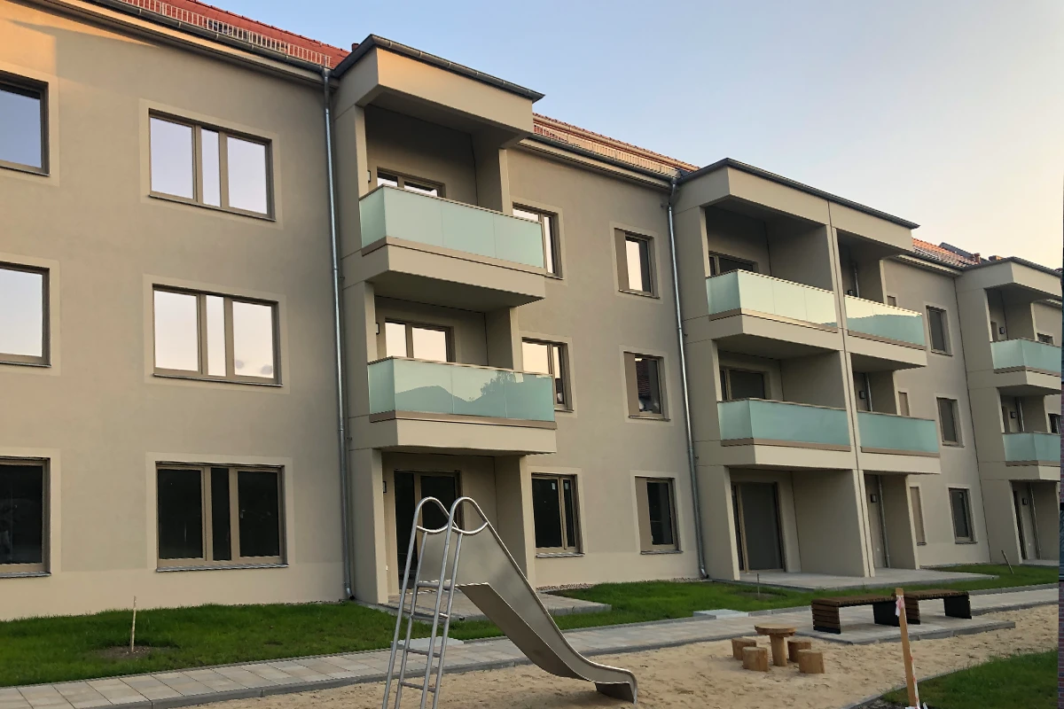 Mehrfamilienhaus mit sanierter Fassade, Balkonen und Spielplatz im Innenhof nach professioneller Fassadensanierung mit Wärmedämmverbundsystem.